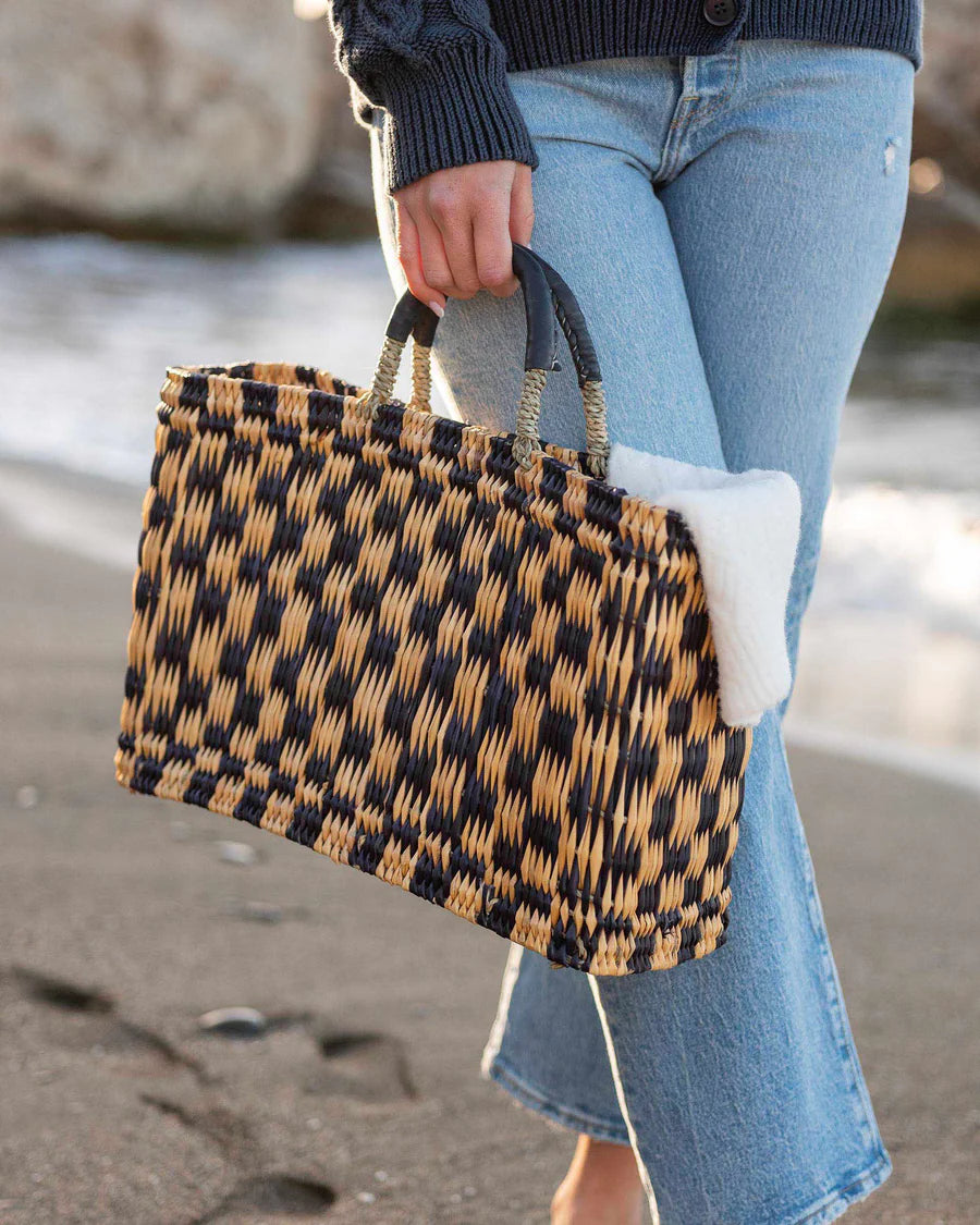 black and natural checkered pattern hand woven market tote bag. Made of straw, palm leaves, and natural leather. 