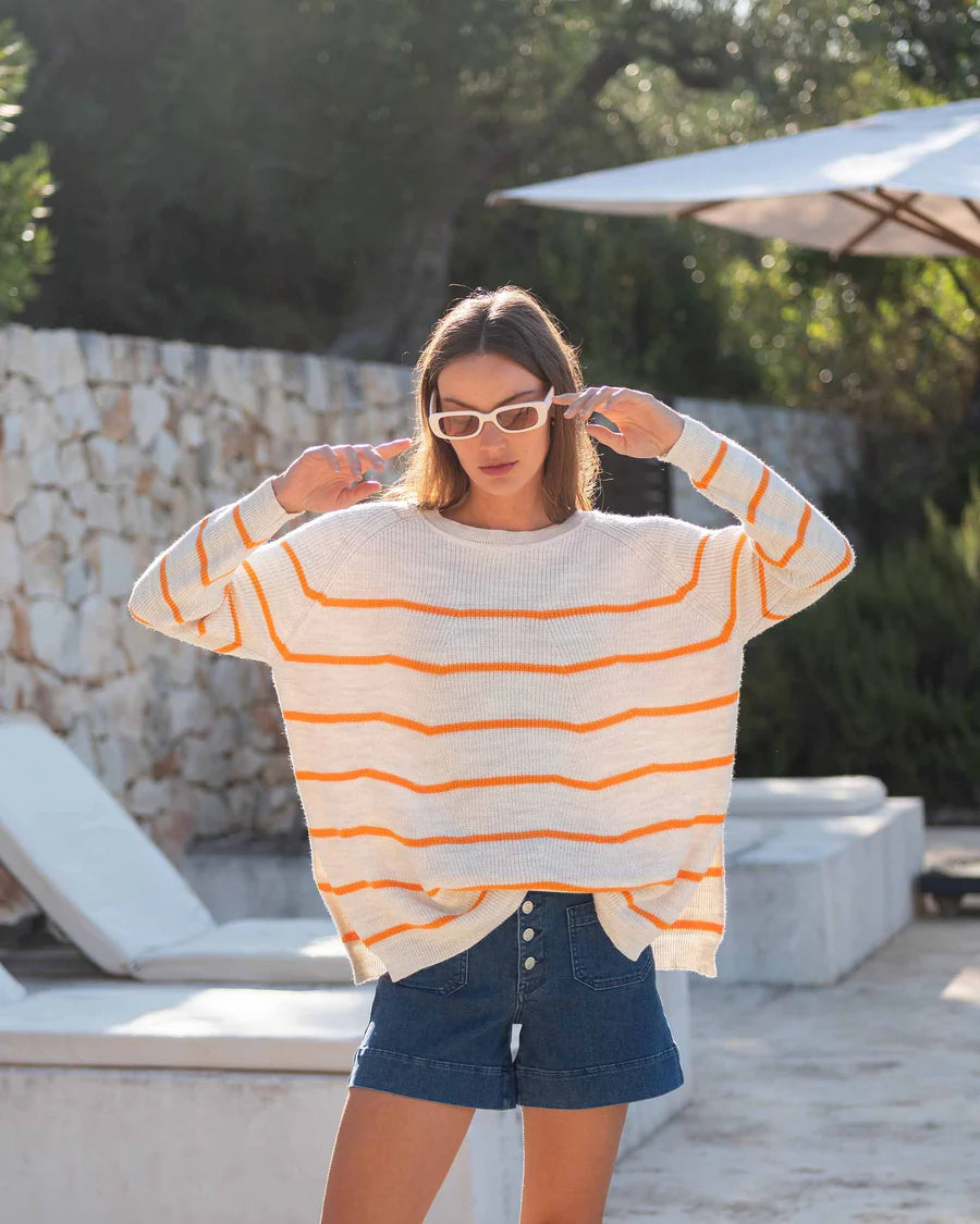 Woman wearing white Camden sweater with bright orange stripes