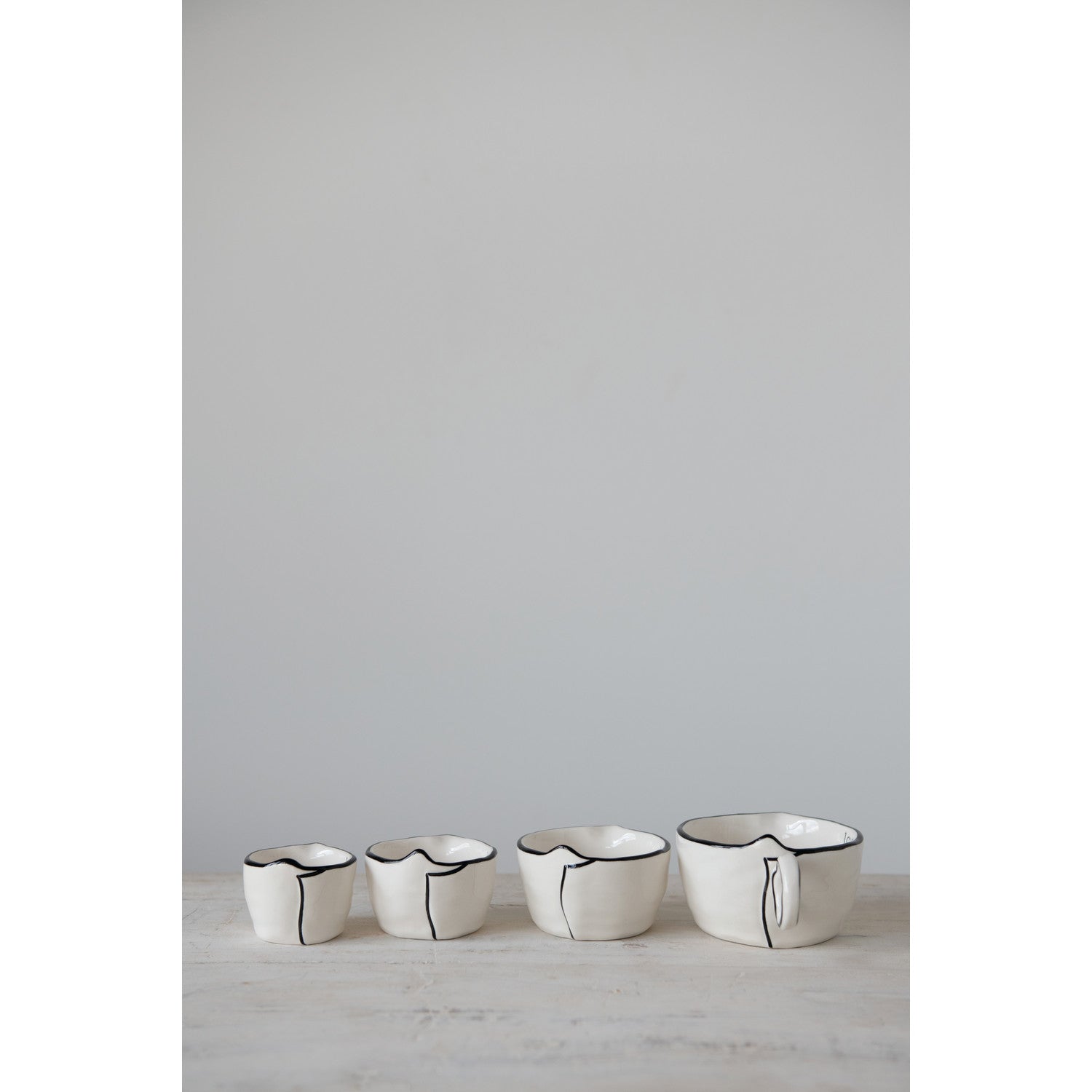 set of four ceramic black rimmed measuring cups. 
