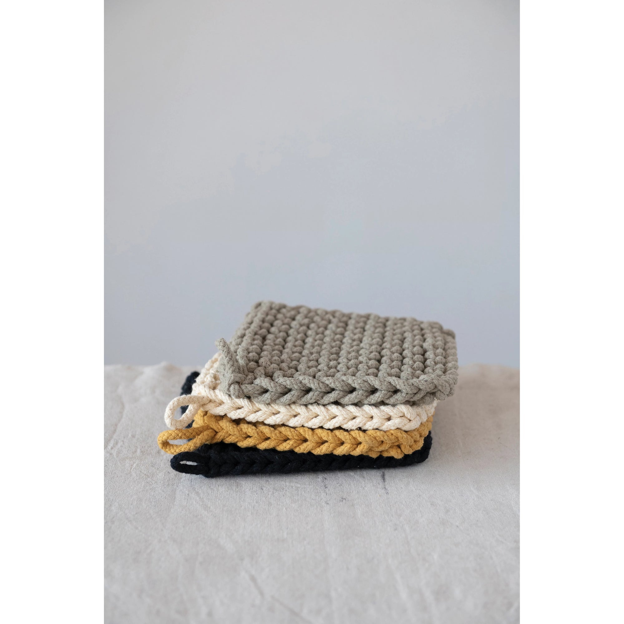 Stacked warm color collection of crocheted pot holders. Taupe, cream, yellow ochre, and black. 