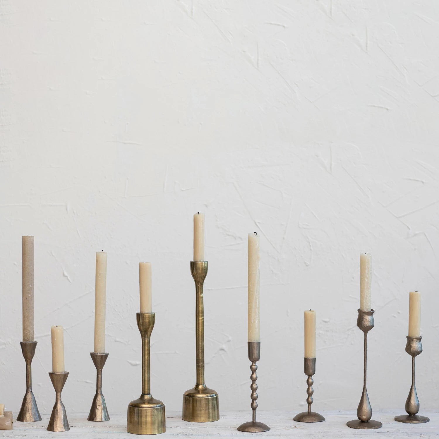 Coordinating and contrasting hammered gold candle taper holders in varying styles and sizes. 