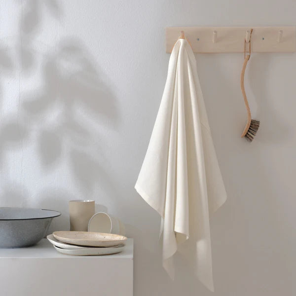 Stone kitchen 100% organic cotton towel hanging from a wood rack in the dappled sunlight.