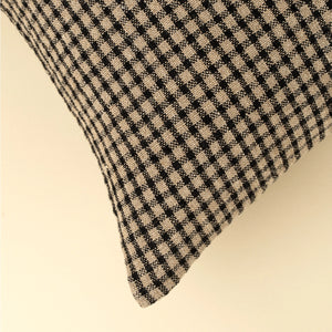 Close up picture of corner edge; Twenty inch square feather down decorative pillow in a classic black and cream mini windowpane stripe pattern. 