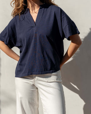 Person wearing a navy blue cotton tee shirt and light-colored pants against a plain background.