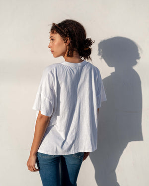 Person wearing a white oversized t-shirt against a light background, side profile view. 