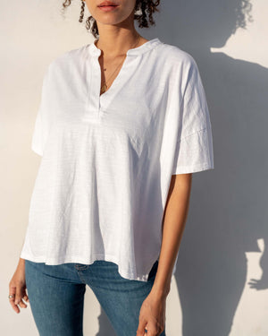 Person wearing a white oversized cotton tee shirt and blue jeans against a plain background.