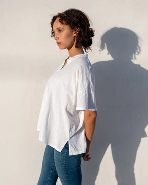 Person wearing a white shirt and blue jeans against a light background