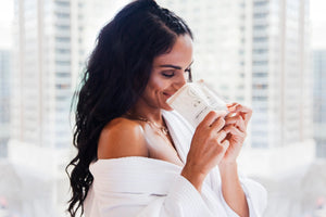 Woman smelling a package of ancient oat hydration bath soak. Bathorium. 