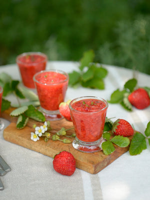 Two ounce french inspired Bee emblem shot glass displayed on table as a set with frozen strawberry drink. La Rochere. French barware and glassware. 