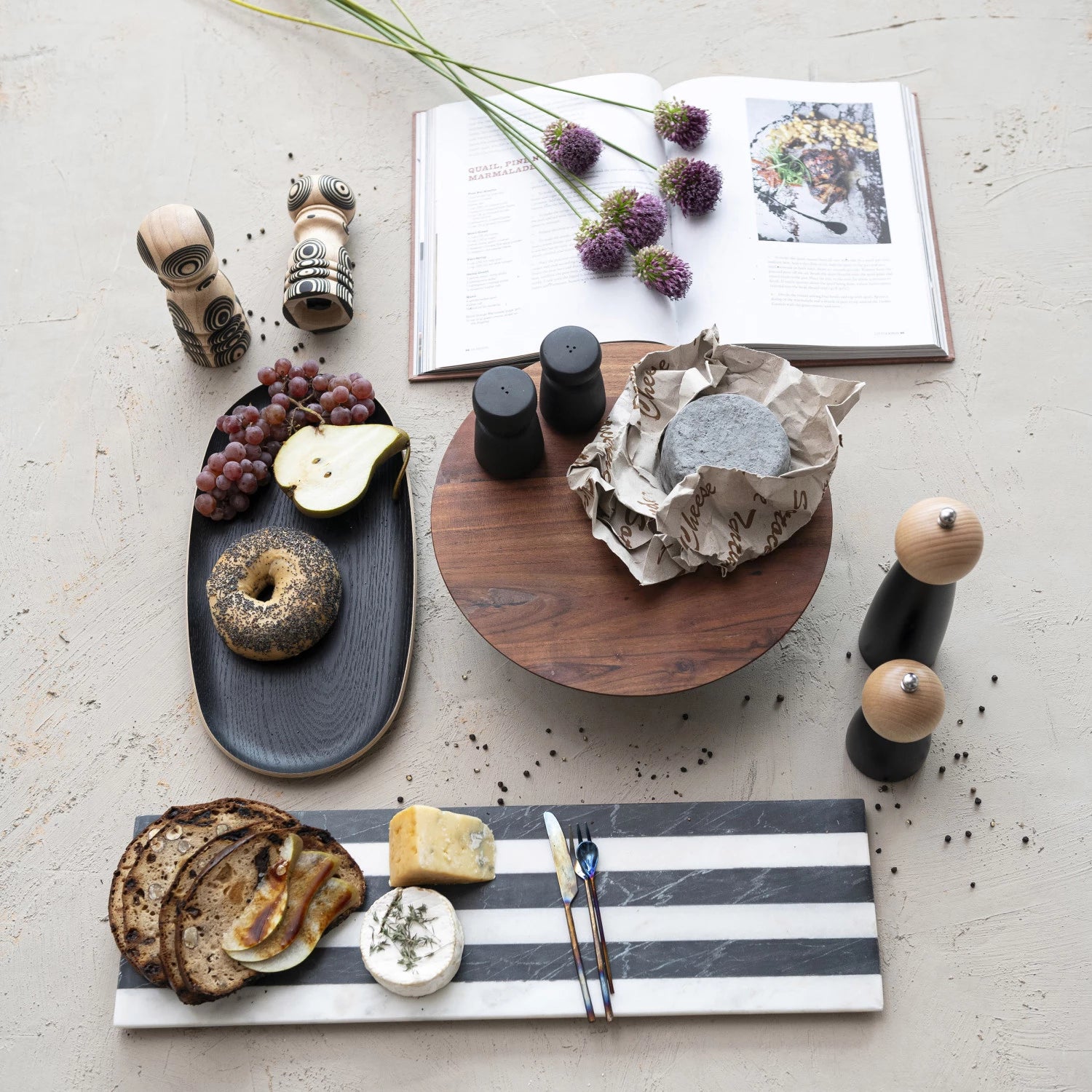 Black oak wood oval serving tray displayed on counter with other charcuterie boards and marble cutting boards. 