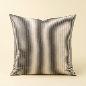 Striped pillow with black and white ticking pattern on a beige background. Pillow size 24 inches square. 