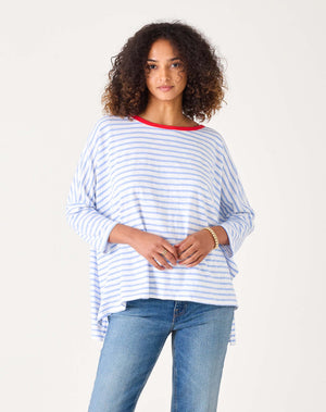 Woman wearing a blue and white striped shirt with a red collar on a plain background.