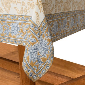 Corner edge detail of blue and gold patterned floral motif square tablecloth. 