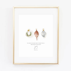 Framed watercolor artwork with Christmas ornaments and scriptural text against a white background. Emily Lex Studios. 