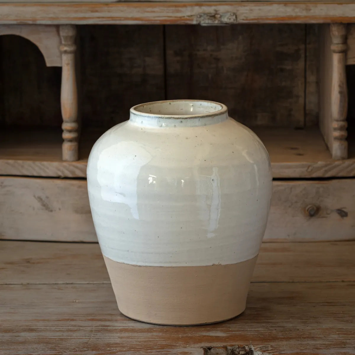 Beige ceramic jar on a wooden surface with a rustic background
