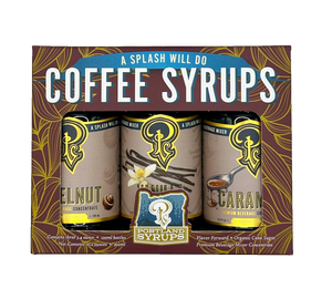 Portland Syrup Company 'A Splash Will Do' coffee syrups gift set in a brown box with gold leaf patterns, featuring three 12 fl oz cans of Nutmeg, Vanilla, and Carafe flavors.