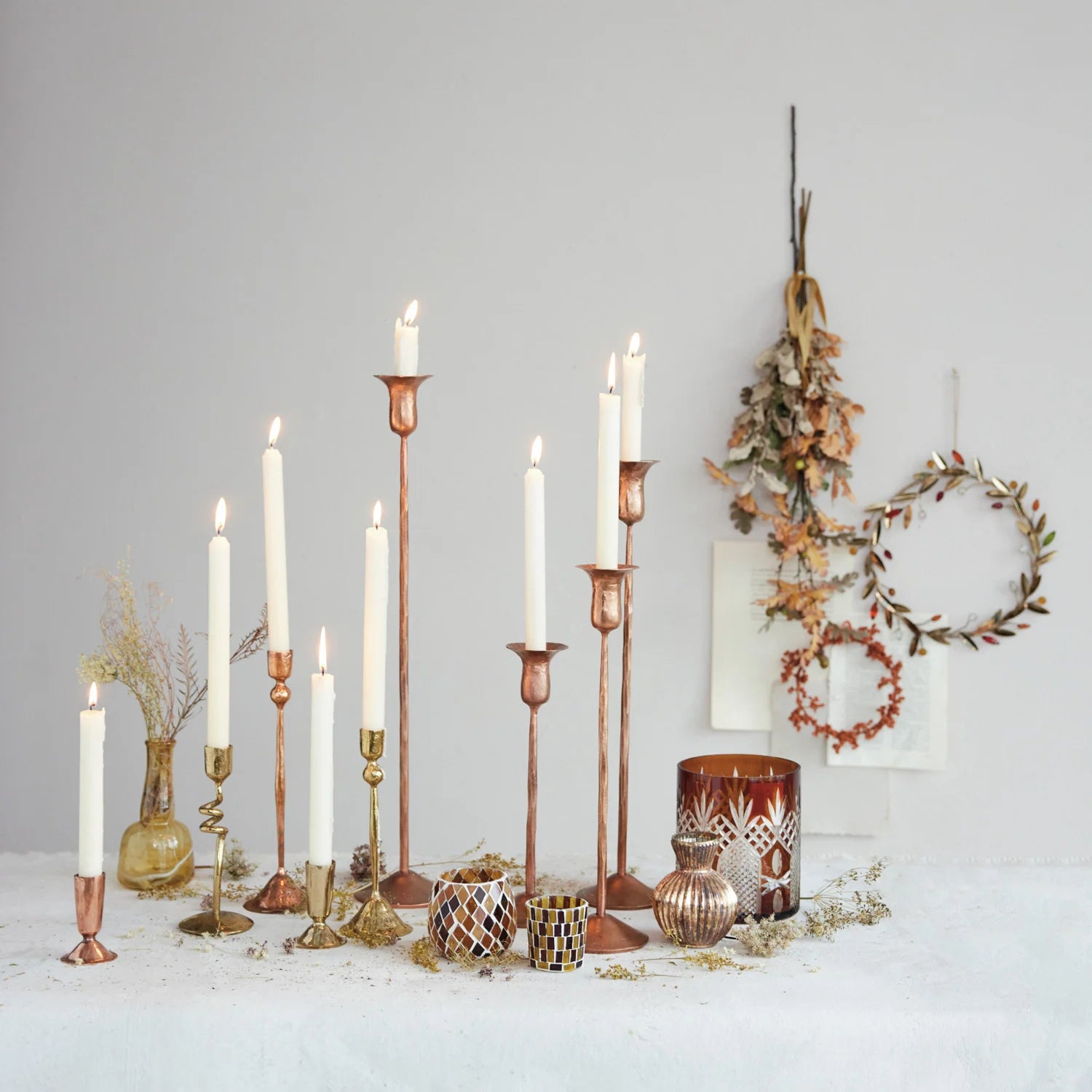 Collection of antique copper candle taper holders in various sizes displayed on a fall themed table. 