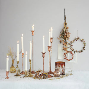 Collection of antique copper candle taper holders in various sizes displayed on a fall themed table. 