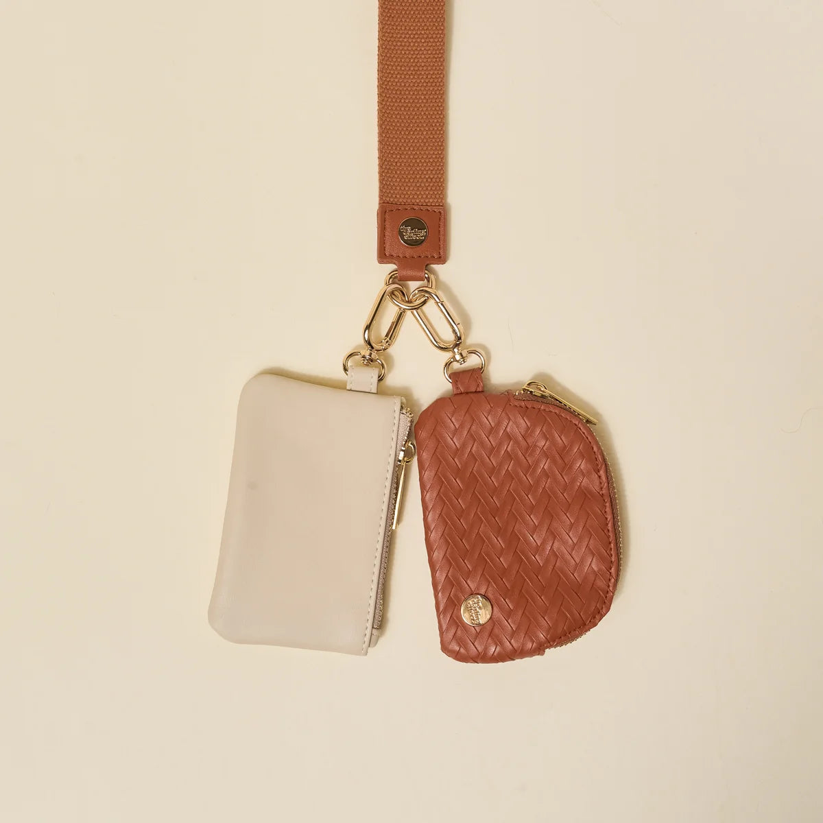 Ivory and cognac brown pouches on a key chained wristlet. 