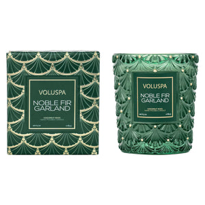 Voluspa Noble Fir Garland coconut wax candle shown next to its matching green and gold patterned box on a plain white background.
