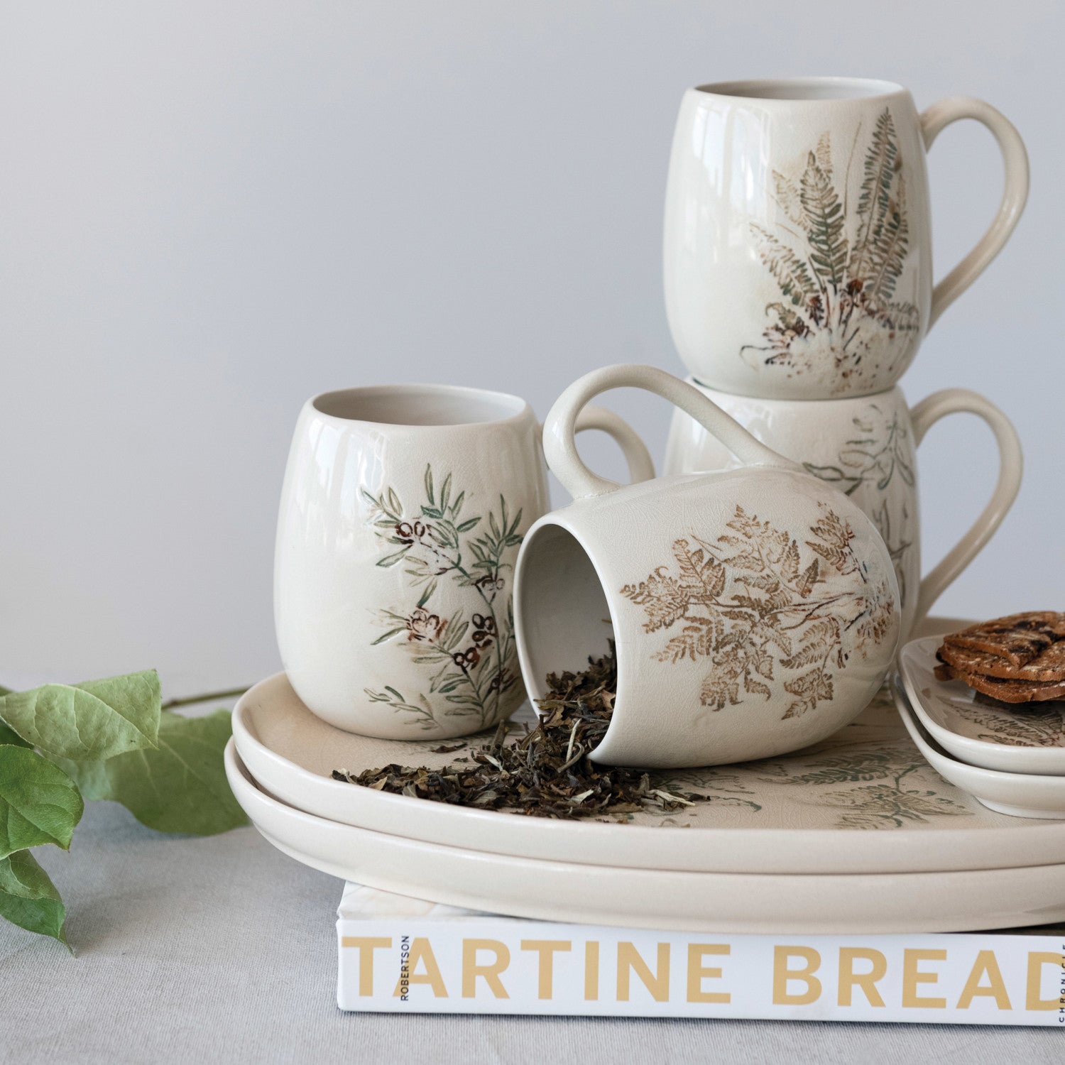 Set of ceramic mugs with floral patterns on a book titled 'Tartine Bread'.