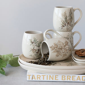 Set of ceramic mugs with floral patterns on a book titled 'Tartine Bread'.