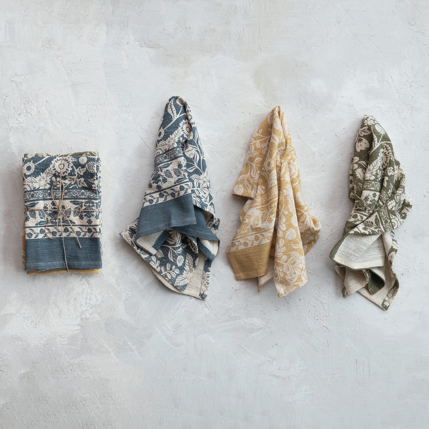 Floral printed cotton kitchen towels in slate blue, yellow ochre, and olive green. 