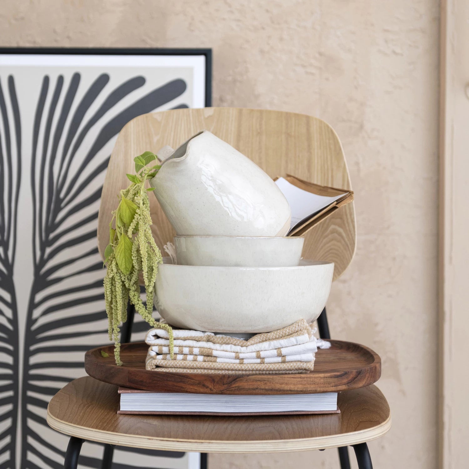 Footed stoneware bowls stacked on wood chair in varying sizes. Artisan kitchen bowls. 