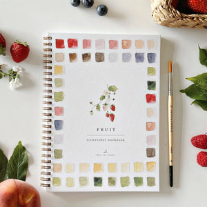 Watercolor workbook titled 'Fruit' with a pen and fruits on a white surface. Emily Lex Studios