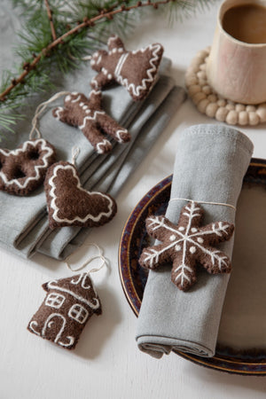 Various decorative wool ornaments on a table with a napkin and cup.