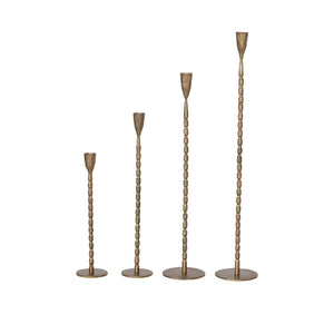 Set of four brass cast iron hammered candle holders displayed in a row. 