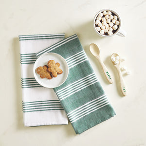Green and white striped towel with a plate of cookies, marshmallows, and wooden spoons on a light background
