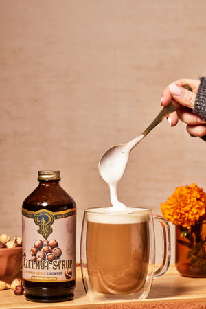 Hazelnut Syrup bottle next to glass latte mug. Portland Syrups. 