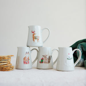 Set of four creamer mugs with festive holiday themed animal illustrations on a light background.