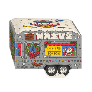 A novelty chocolate bonbon box shaped like a decorated Christmas delivery truck, featuring the brand name 'Maeve' and holiday illustrations including Santa, a wreath, lights, and snow on a white background.