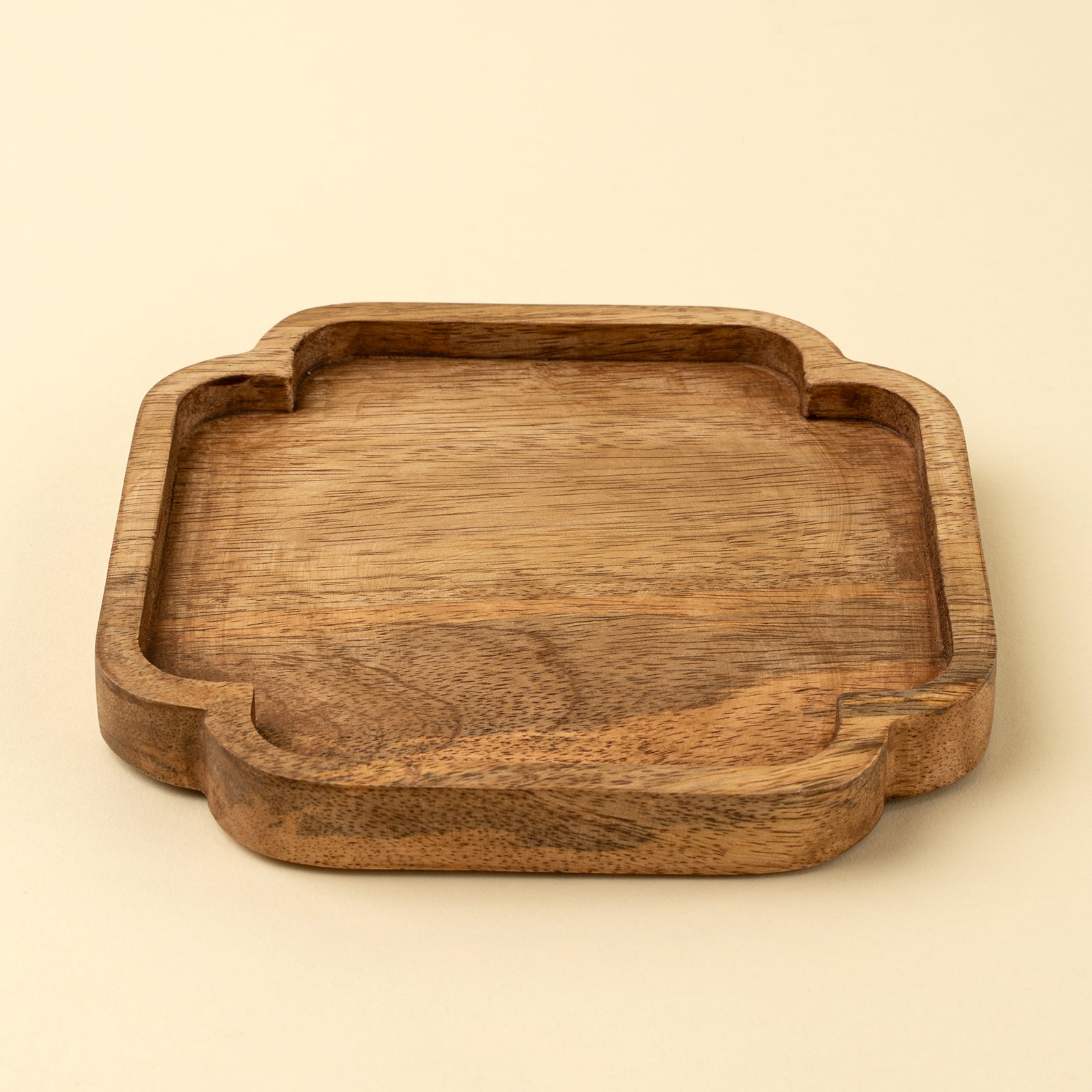 A square wooden tray with rounded corners and a carved decorative edge, shown on a plain light beige background.