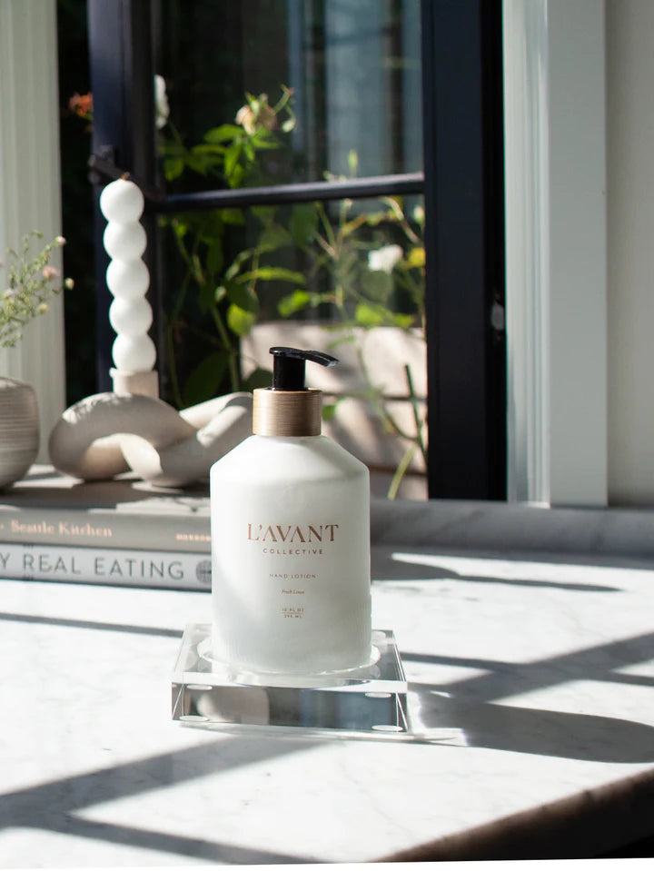 Clear Lucite tray displaying a matte white bottle of LAVANT high performing hand lotion. 