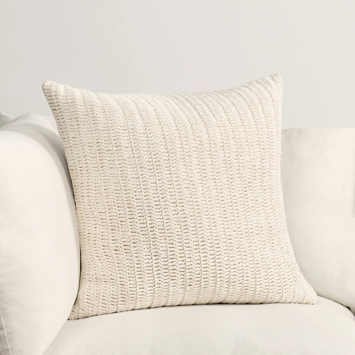 Hand knotted textural ivory pillow on a light gray sofa.