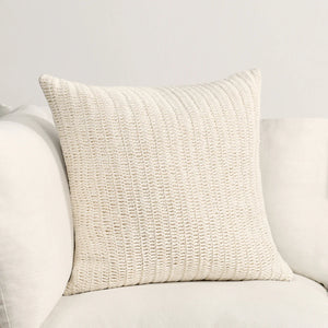 Hand knotted textural ivory pillow on a light gray sofa.