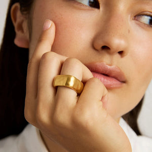 Close-up of a woman's hand wearing  a hammered gold square edge chunky gold fashion ring. Dean Davidson jewelry. 