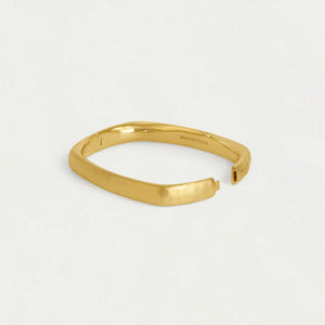 Gold bangle bracelet displayed open on a white background. Dean Davidson jewelry. 