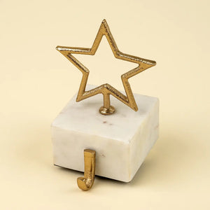 Solid marble base stocking hanger with a gold star atop against a beige background.