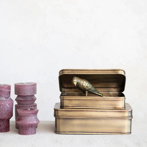 Antique brass decorative storage tins with a decorative bird figurine displayed inside on a white background