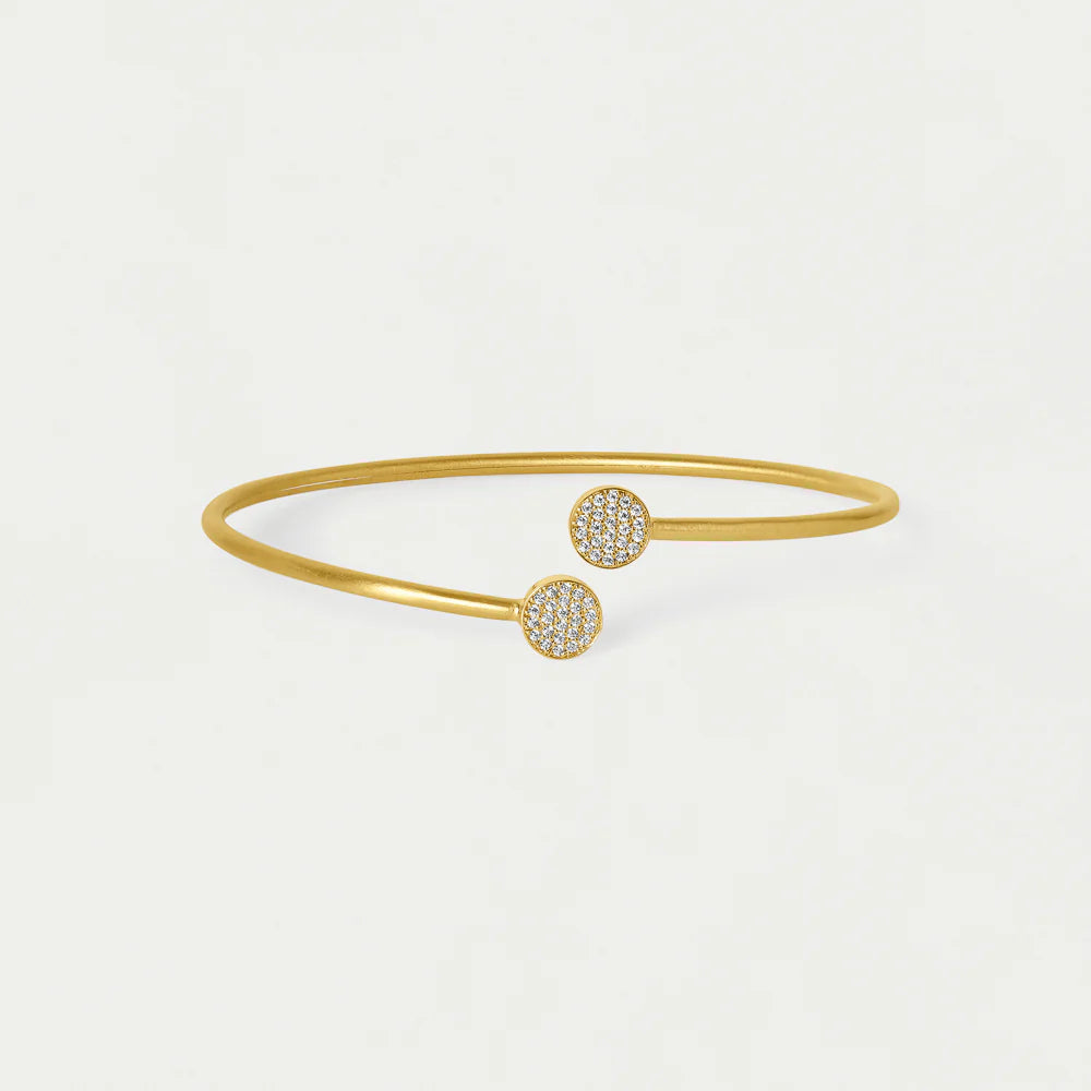 Gold bangle bracelet with round end cubic zirconia embellishments on a white background. Dean Davidson jewelry
