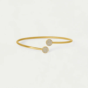 Gold bangle bracelet with round end cubic zirconia embellishments on a white background. Dean Davidson jewelry