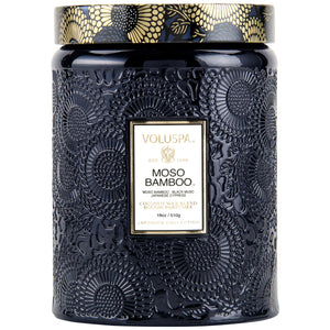 18 ounce glass jar candle with embossed design and gold lid on a white background. Voluspa Moso Bamboo. 
