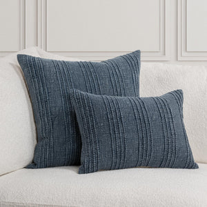 Twenty-two inch and lumbar decorative navy blue textured stripe pillows on a white sofa against a light gray wall.