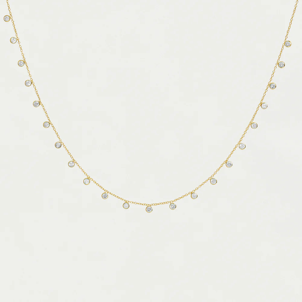 Gold necklace chain with small cubic zirconia pendants on a light gray background. 