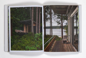 Open book showing a scenic lush green forest cabin by a lake nestled into trees. "Pacific Natural Everywhere" by Jenni Kayne. 