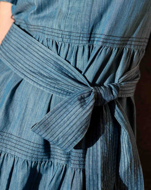 Close-up of a blue cotton dress with a tie bow waist. Mersea. 